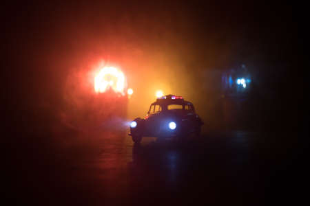 Police car chasing a car at night with fog background. 911 Emergency response police car speeding to scene of crime. Creative decoration. Selective focusの写真素材
