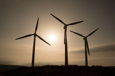 Electricity power in nature or clean energy concept. Wind Turbine producing alternative energy on hill during sunset time. Creative decoration with small miniature. Selective focusの写真素材