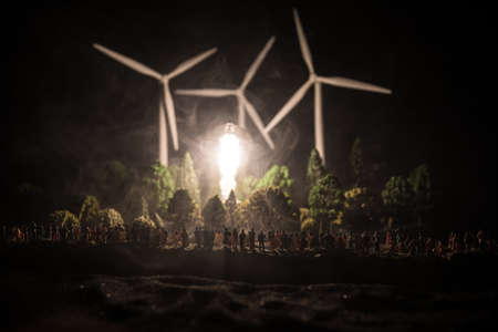 Electricity power in nature or clean energy concept. Wind Turbine producing alternative energy at night. Glowing bulb powered by alternative energy. Creative decoration with small miniature. Selective focusの写真素材