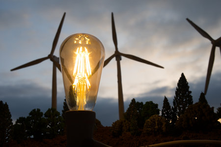 Electricity power in nature or clean energy concept. Wind Turbine producing alternative energy at sunset. Creative decoration with small miniature. Selective focusの写真素材