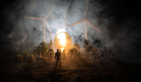 Electricity power in nature or clean energy concept. Wind Turbine producing alternative energy at night. Glowing bulb powered by alternative energy. Creative decoration with small miniature. Selective focusの写真素材