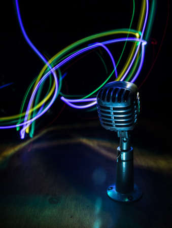Retro style microphone on background with backlight. Vintage silver Microphone for sound, music, karaoke. Speech broadcast equipment. Live pop, rock musical performance. Selective focusの写真素材