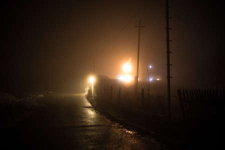Night street country road with buildings and fences covered in fog lamp. Or Mysterious night in Azerbaijan mountain village. Long exposure shotの写真素材