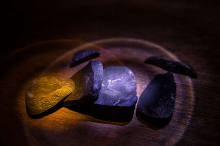Parts of broken stone on a wooden table. Colorful lights on stones in selective focus. Close upの写真素材