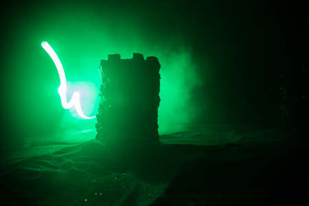Stone defense tower at night. Medieval castle miniature with toned foggy backlight. Creative table decoration. Selective focusの写真素材
