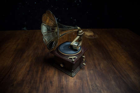 Music concept. Old gramophone on a dark background. Retro gramophone with disc on wooden table with toned backlight. Selective focusの写真素材