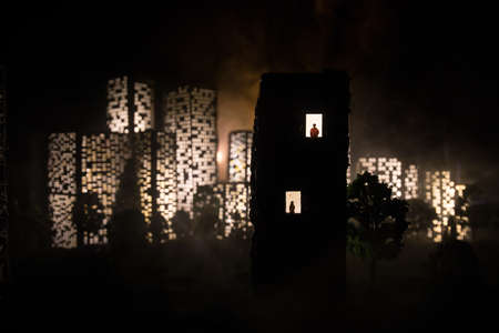 concept of loneliness, in the form of a silhouette of woman and man in a city window at night. Symbol of expectation, dreams and destinies. Creative decoration with City miniature. Selective focusの写真素材