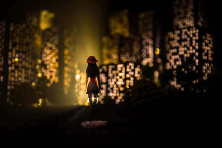 Cartoon style city buildings. Realistic city building miniatures with lights. background. Girl looking on night city. Selective focusの写真素材