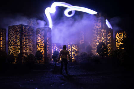 Cartoon style city buildings. Realistic city building miniatures with lights. background. Silhouette of a man looking on night city. Selective focusの写真素材