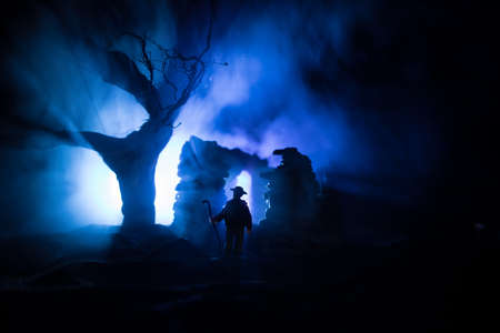 Old ruined stone house in deserted garden at night. Abandoned old mystic building with dead tree and...