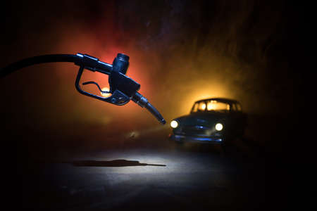 Creative concept. Silhouette of gasoline pistol miniature on dark toned foggy background. Close up....