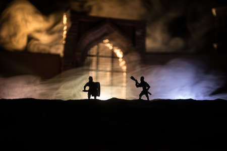 Medieval battle scene. Silhouettes of figures as separate objects, fight between warriors at night. Creative artwork decoration. Foggy background. Selective focusの写真素材
