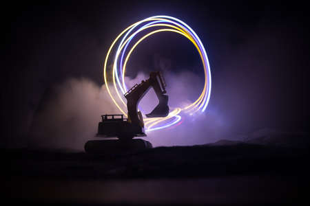 Construction site on a city street. A yellow digger excavator parked during the night on a...