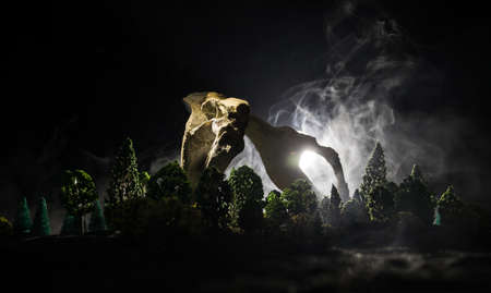 Abstract surreal concept. Giant animal bone in dark forest under moonlight. Night with fog and light on background. Selective focusの写真素材