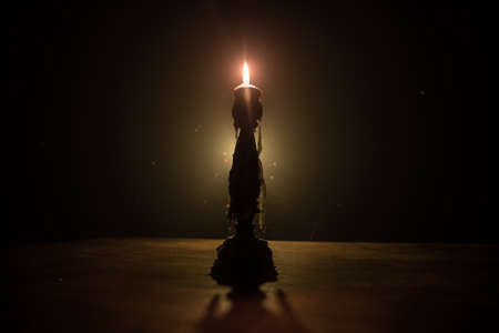 Single burning candle. Light of flame and flowing candle wax, dark background. Selective focus