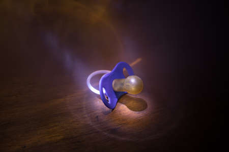 Baby pacifier on wooden table with low key toned background. Selective focusの写真素材