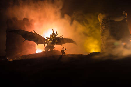 Fantasy battle scene with dragons attacking a medieval castle at night. Battle between dragon and heroic soldiers. Creative table decoration. Selective focusの写真素材
