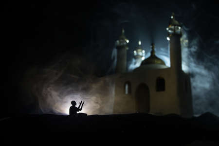 Silhouette of mosque building on toned foggy background. Ramadan Kareem background. Realistic mosque miniature with prayer silhouette. Selective focusの写真素材