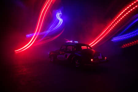 Police car chasing a car at night with fog background. 911 Emergency response police car speeding to scene of crime. Creative decoration. Selective focusの写真素材