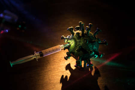 Corona virus Vaccine concept with syringe and green Corona virus novel miniature. Vaccine Concept of fight against coronavirus. Creative decoration with fog and backlight. Selective focusの写真素材