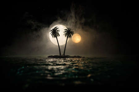 Romantic night scene. Fantasy night landscape with little island with palms and full moon over sea. Table decoration with two moon miniatures. Fantasy tropical beach. Selective focus.の写真素材