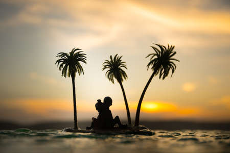 Romantic sunset scene. Fantasy landscape with little island with palms on sunset. Creative table decoration. Fantasy tropical beach. Selective focus.の写真素材