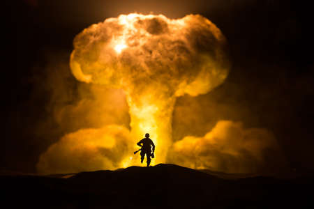 Nuclear war concept. Explosion of nuclear bomb. Creative artwork decoration in dark. Silhouette of soldier standing against giant mushroom cloud of atomic explosion. Selective focusの写真素材