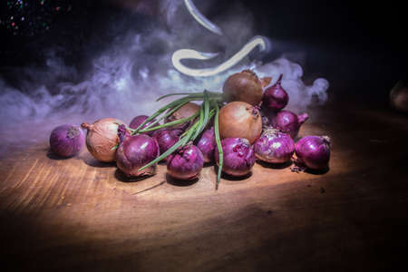 Vegetable concept. Different onions on wood in dark. Selective focus. Colorful background.の写真素材