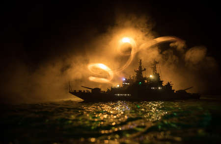War concept. Night battle scene at sea. Dramatic toned clouds effect. Silhouette of the battle ship in night. Miniature creative table decoration. Selective focusの写真素材