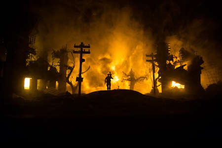 Silhouette soldier carrying little boy on his shoulder from fire. Rescue savior concept. Man moving out with little boy from burned out city destroyed in war. Selective focusの写真素材