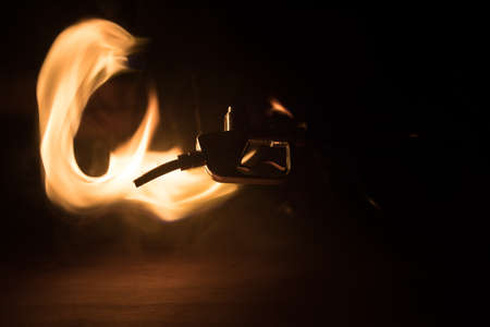 Creative concept. Silhouette of gasoline pistol miniature on dark toned foggy background. Fuel gun close up burning. Selective focusの写真素材