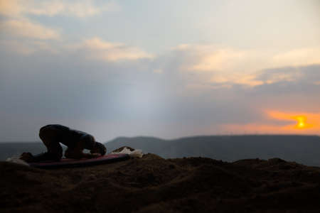 Silhouette of muslim prayer on sunset. Ramadan Kareem background. Praying people. Selective focus