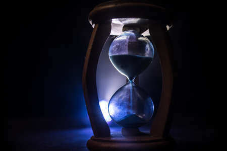 Time concept. Silhouette of Hourglass clock on dark toned background. Abstract concept with copy...