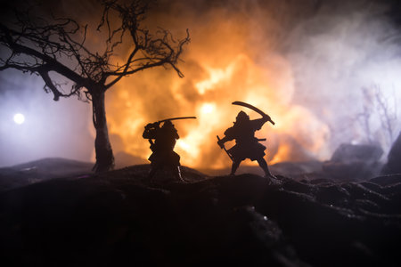 Samurai fighting concept. Silhouette of samurais in duel near tree and old temple. Table decoration with dark toned foggy background. Selective focusの写真素材