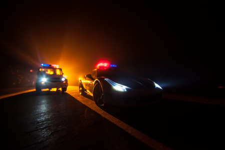 Police car chasing a car at night with fog background. 911 Emergency response police car speeding to...