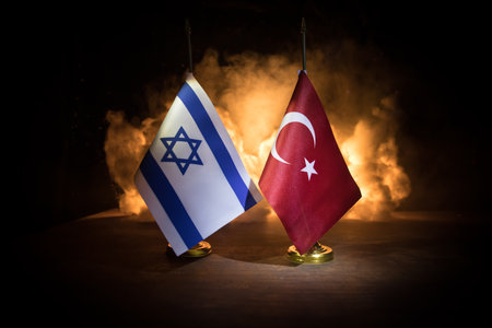 Israel and Turkey small flags on burning dark background. Concept of crisis of war and political conflicts between nations. Selective focusの写真素材
