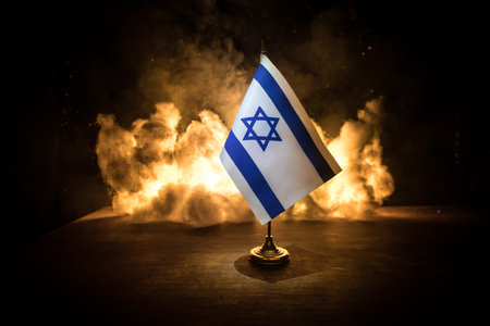 Israel small flag on burning dark background. Concept of crisis of war and political conflicts between nations. Selective focusの写真素材