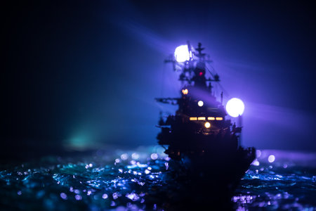 War concept. Night battle scene at sea. Dramatic toned clouds effect. Silhouette of the battle ship in night. Miniature creative table decoration. Selective focusの写真素材