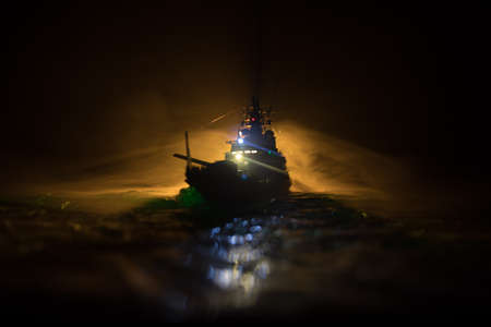 War concept. Night battle scene at sea. Dramatic toned clouds effect. Silhouette of the battle ship in night. Miniature creative table decoration. Selective focusの写真素材