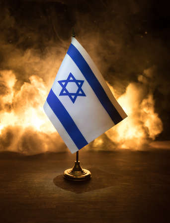 Israel small flag on burning dark background. Concept of crisis of war and political conflicts between nations. Selective focusの写真素材