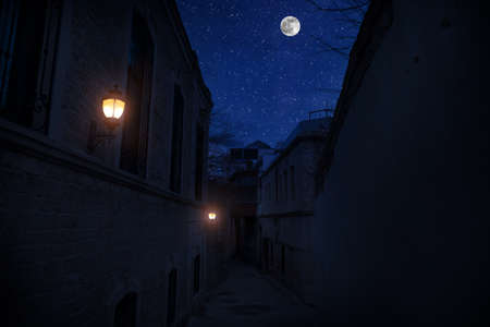 Old city streets at night. Full moon over the city at night, Baku Azerbaijan. Big full moon shining bright over buildingsの写真素材