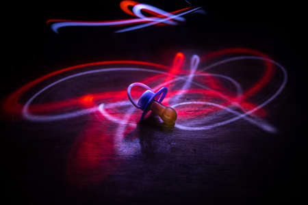 Baby pacifier on wooden table with low key toned background. Selective focusの写真素材