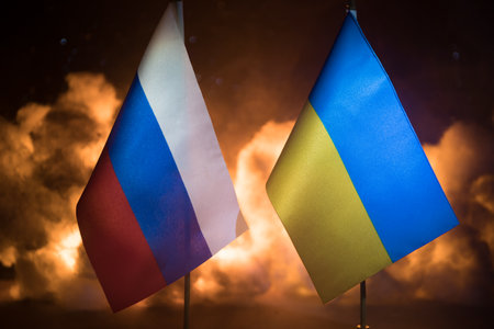 Concept of crisis of war and political conflicts between countries. Russia and Ukraine small flags on dark burning background. Selective focusの写真素材