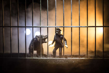 Silhouette of a Bear miniature standing in a zoo cage with scared man ready to attack. Creative...