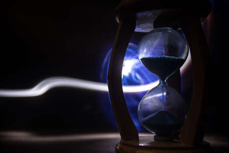 Time concept. Silhouette of Hourglass clock on dark toned background. Abstract concept with copy...