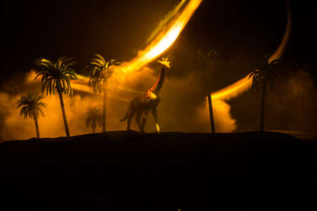Silhouette of a giraffe miniature standing at foggy night. Creative table decoration with colorful backlight with fog. Selective focusの写真素材