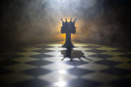 Beautiful crown miniature on chessboard. chess board game concept of business ideas and competition and strategy ideas concept. Chess figures on a dark background with smoke and fog. Selective focusの写真素材