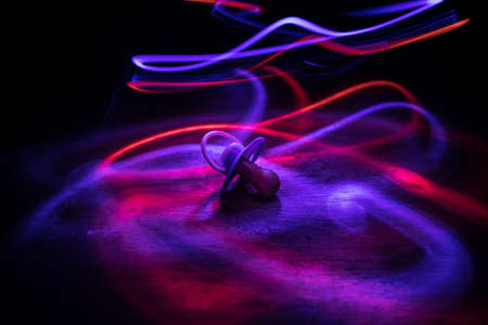 Baby pacifier on wooden table with low key toned background. Selective focusの写真素材