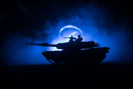 War Concept. Armored vehicle silhouette fighting scene on war foggy sky background at night. American tank ready to fight. Creative decorationの写真素材