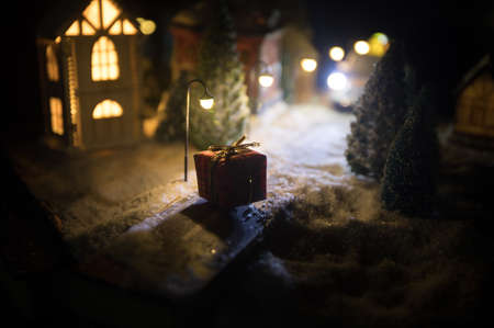 Little decorative cute small houses in snow at night in winter, Christmas and New Year miniature house in the snow at night with fir tree. Holiday concept. Selective focusの写真素材